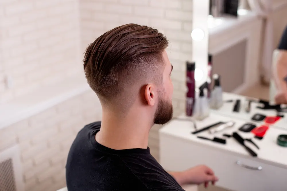 Slicked-back men’s haircut with a skin fade